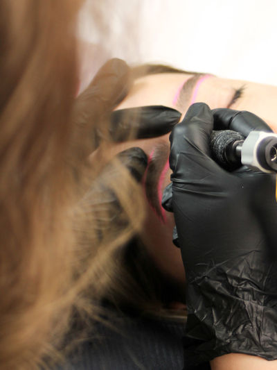 Cosmetologist applying permanent make up eyebrows for a client in a salon