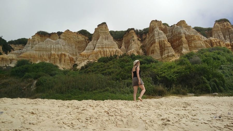 Woman walking on sand against mountain