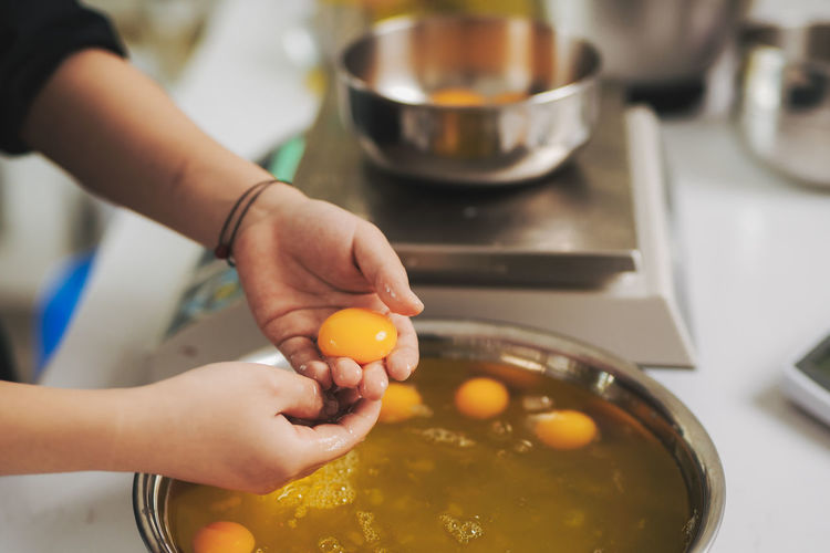 Cropped hands of woman preparing eggs in kitchen