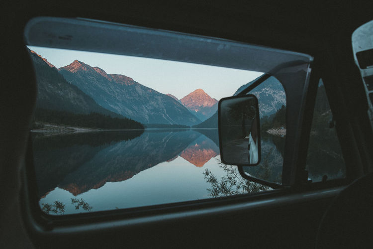 Scenic view of lake and mountains seen through car window