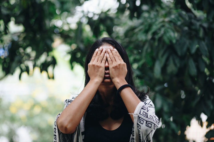 Mid adult woman covering eye in park