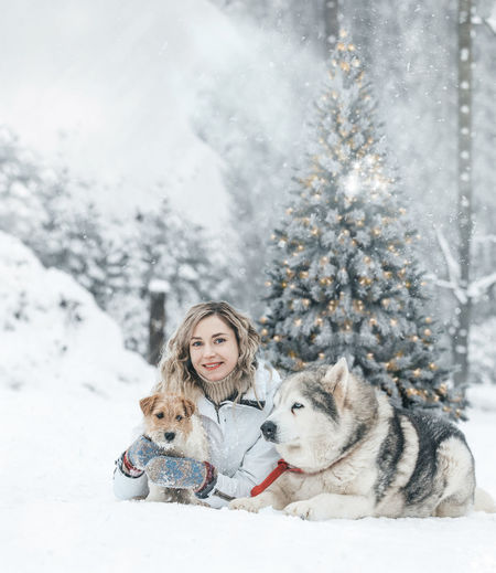 The girl rides on a sled on a sled with siberian huskies in the winter forest.