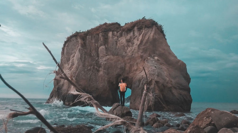 Man standing against rock formation at beach