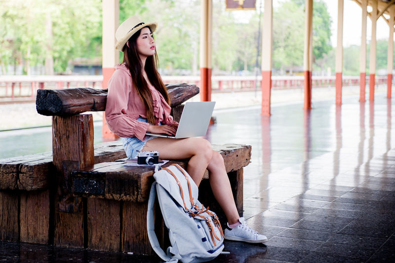 Young woman using mobile phone while sitting in laptop