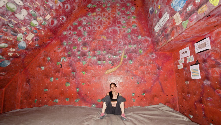 Woman resting on bouldering mat at indoor climbing gym