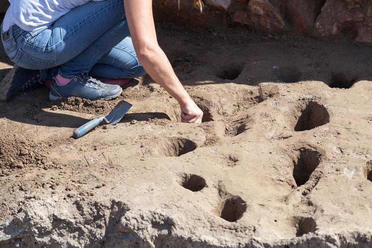 Low section of female archaeologist digging hole