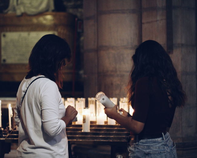 Women standing by illuminated candles in darkroom