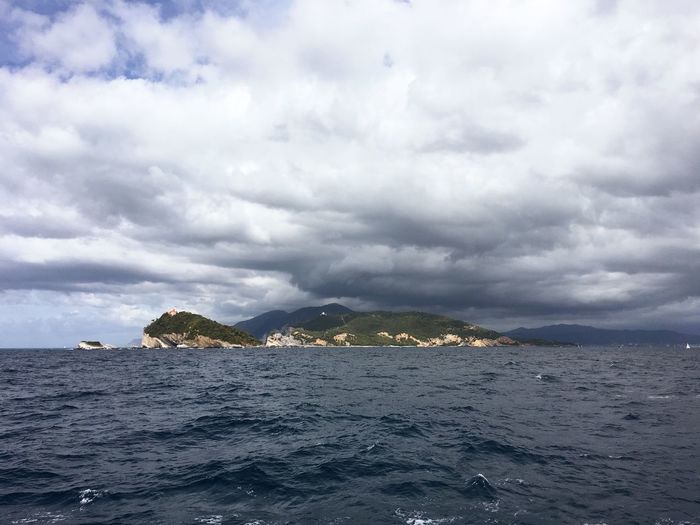 Scenic view of island in sea against cloudy sky