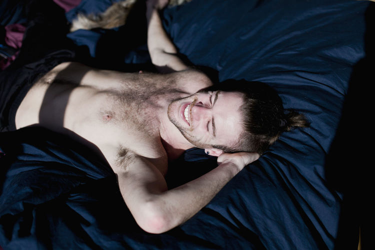 Portrait of young man lying down on bed