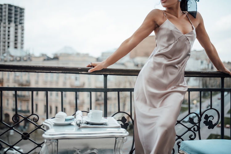 Midsection of woman standing by railing against balcony