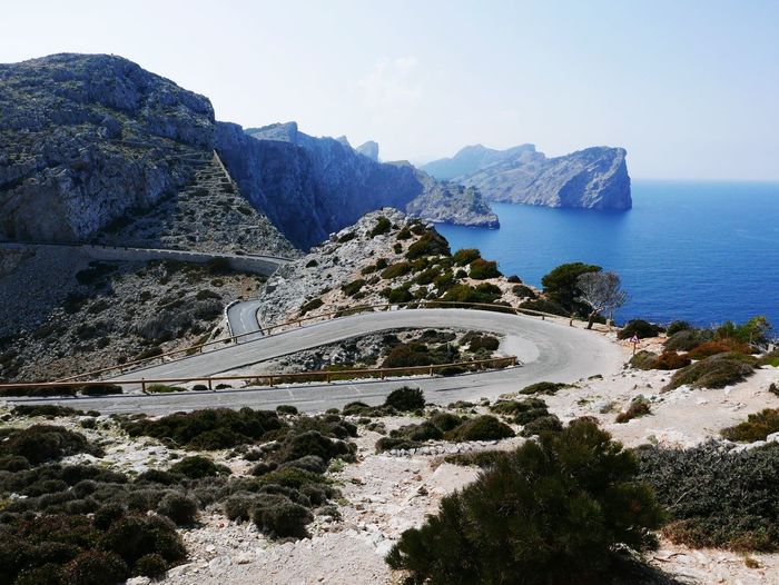Scenic view of road on mountain by sea against sky
