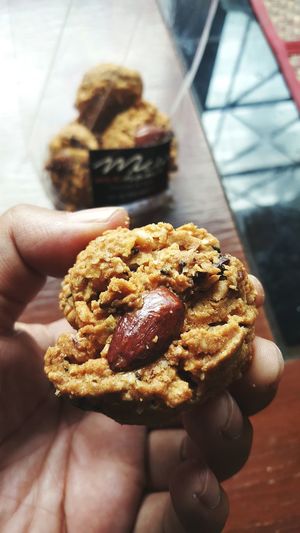 Cropped hand holding cookie at home