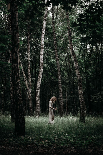 Lonely young woman standing alone in the middle of the forest