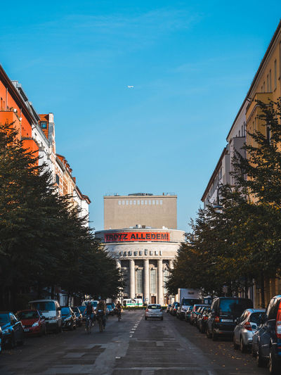 Road by buildings against sky in city