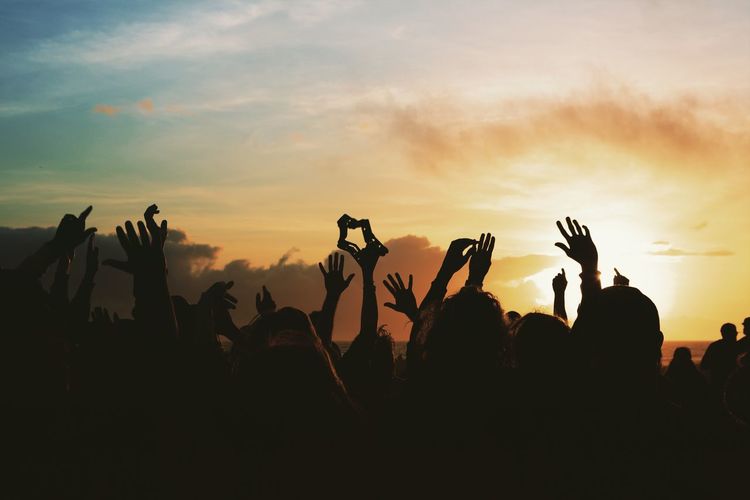 Silhouette people at music concert against sky during sunset