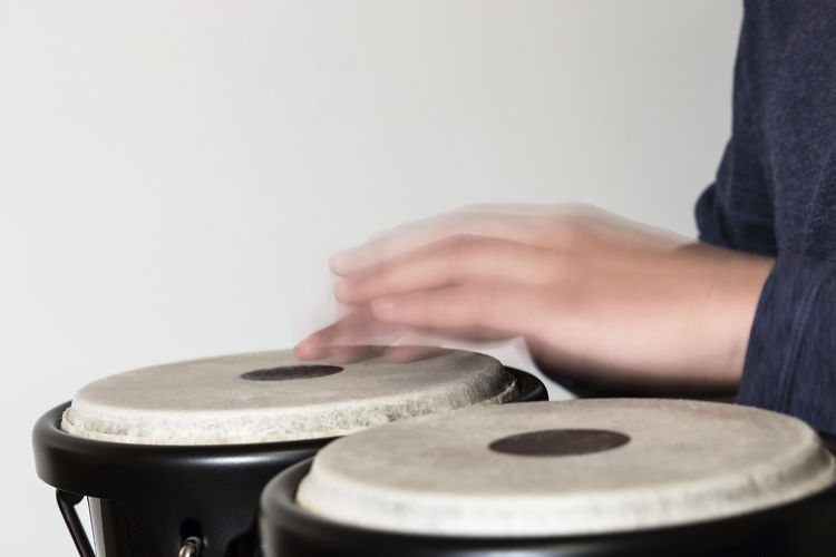 Blurred motion of person playing drums against wall