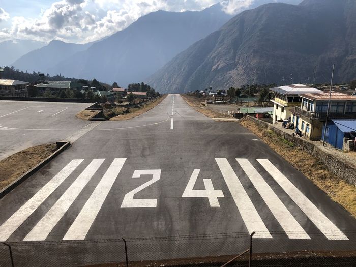 Lukra airport in nepal. road by mountains against sky in city