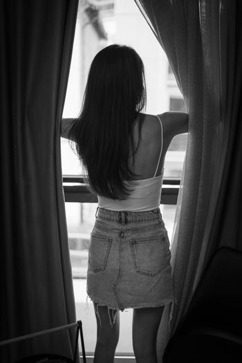 Rear view of woman standing by window