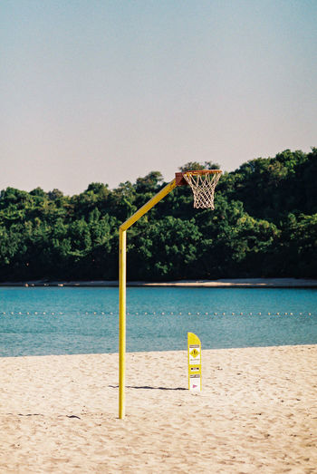 Basketball hoop on beach against clear sky