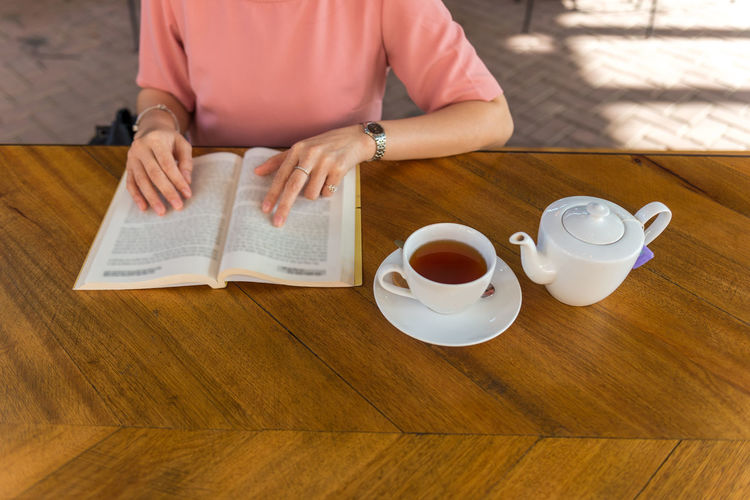 Midsection of woman reading book at table