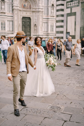 Full length of bridegroom holding hands standing on street