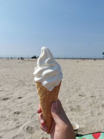 Hand holding ice cream cone on beach