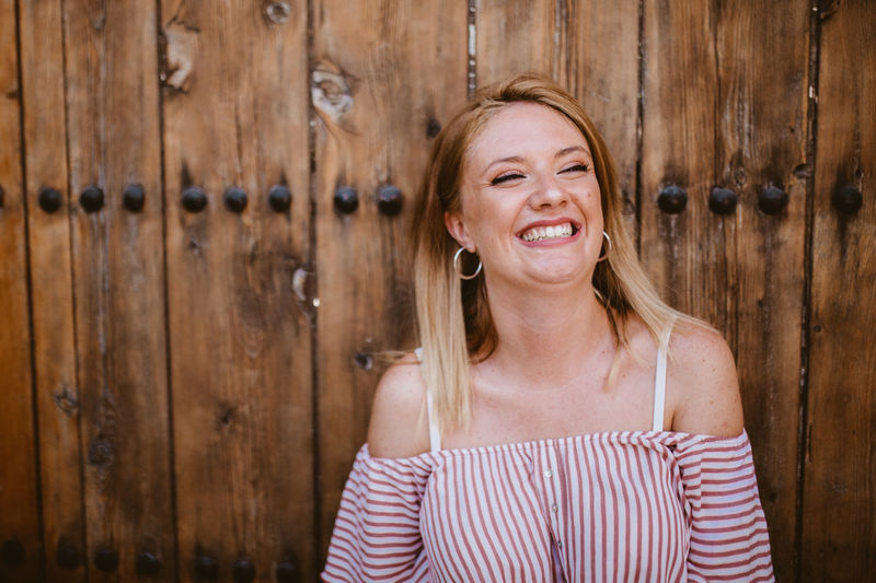 Blonde woman laughing with a old wooden door background