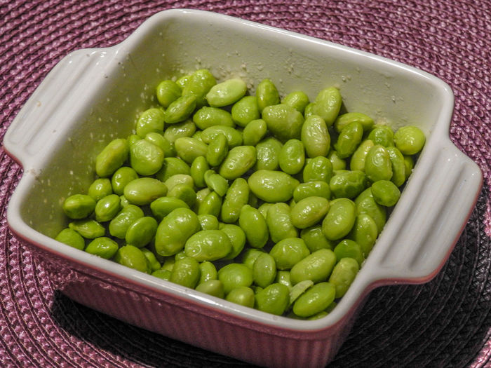 High angle view of edamame beans in container on place mat