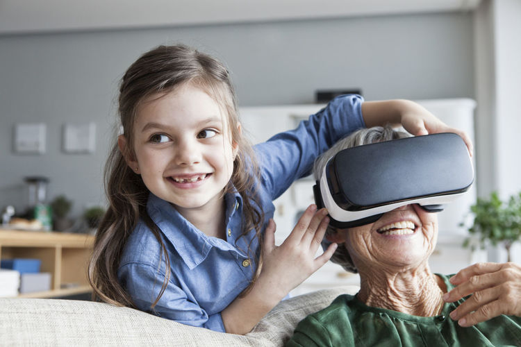 Senior woman and her granddaughter having fun with virtual reality glasses at home