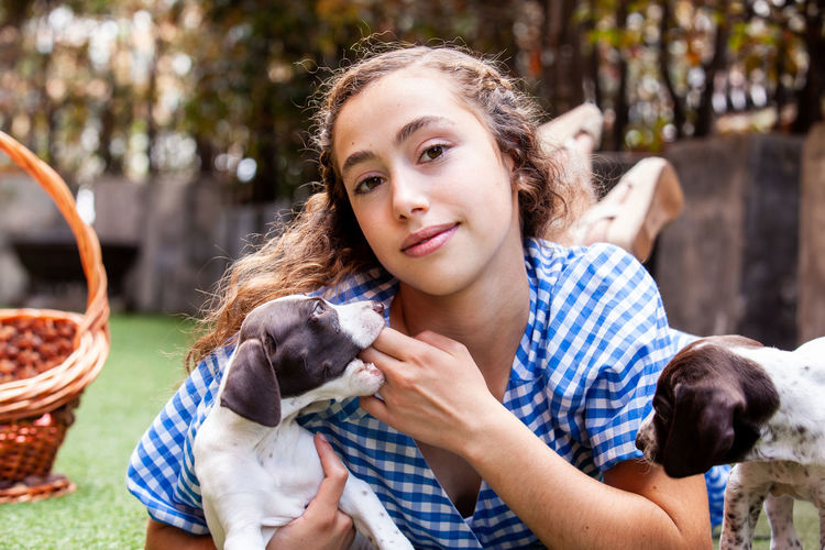 Beautiful young girl having fun with her small french braque puppies