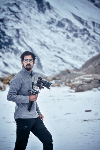 Full length of man photographing on snowcapped mountain