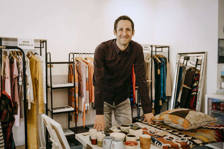 Portrait of smiling male owner standing in clothing store