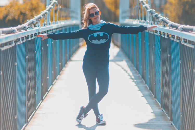 Full length of woman running on footbridge in city