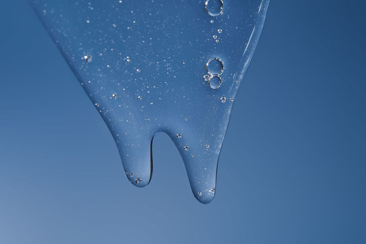 The texture of a gel or shampoo flowing down on a blue background.