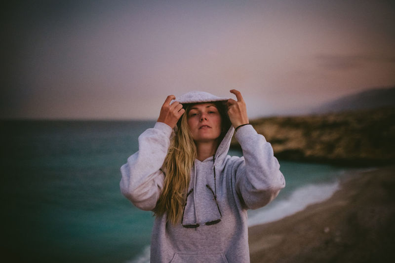 Portrait of woman standing at beach against sky