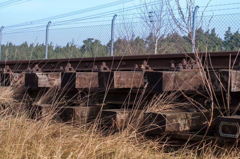 Abandoned railroad tracks on field against sky