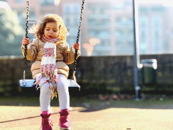 Portrait of a smiling girl on swing in playground