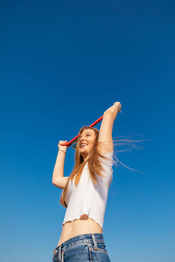 Happy teenage girl holding a skateboard over her head