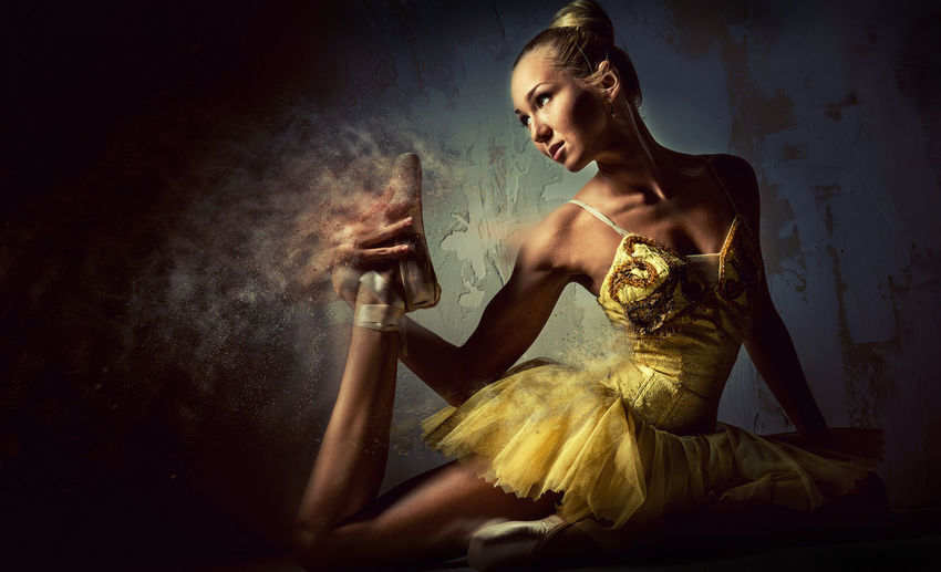 Digital composite image of ballet dancer stretching by wall