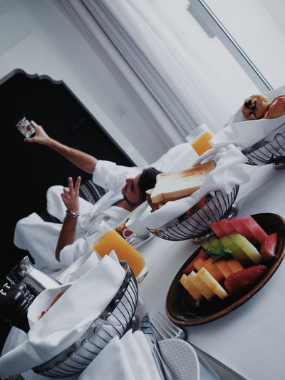Close-up of breakfast on table with man lying on bed in background 