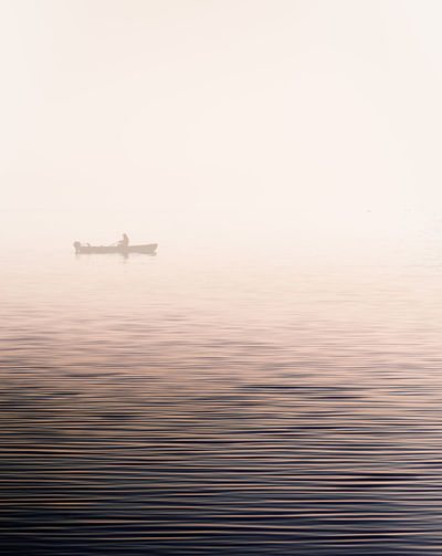 BOAT SAILING IN SEA AGAINST SKY