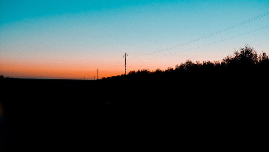 Silhouette of electricity pylon against sky during sunset