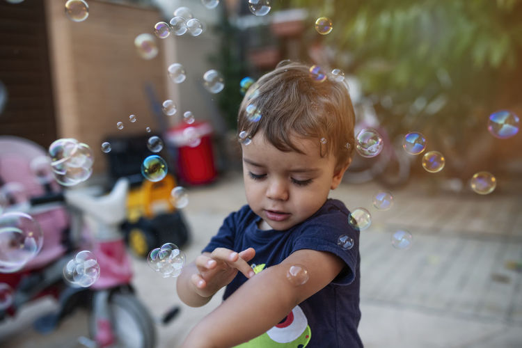 Child with blue t-shirt playing with soap bubbles