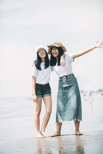 Full length of girls standing at beach against sky