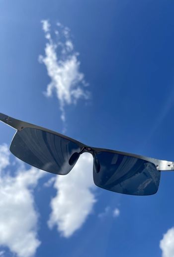 Low angle view of sunglasses against blue sky