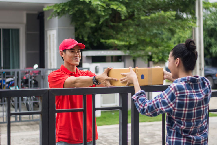 Man delivering package to female customer at gate