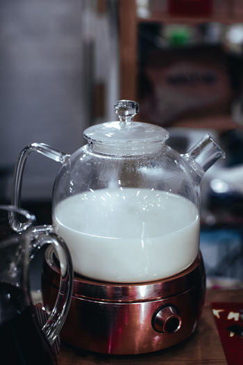 Glass teapot with white steamed milk for making indian masala tea. hot drink. vertical