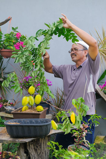 Midsection of man holding flowers in potted plant