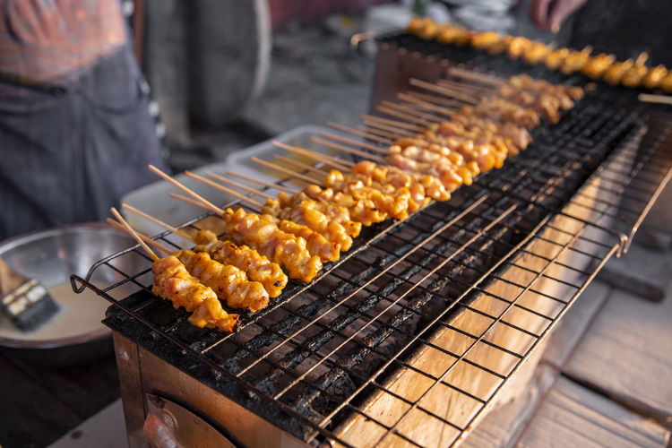 Organic chicken satay grilled on grills plate with smoke. asian thai street food on  night market