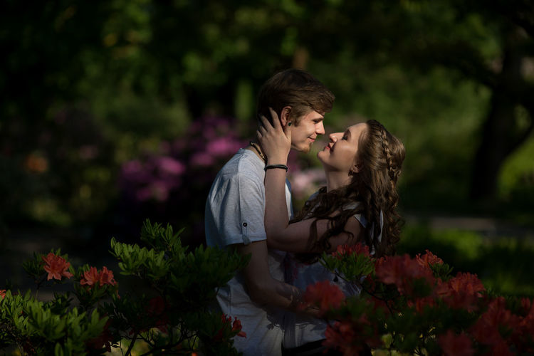 Side view of couple standing amidst flowers at park